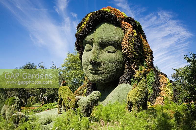 Living plant sculpture in summer called 'Mother Earth' created on metal mesh forms filled with earth and planted with various plants, flowers, grasses and climbing ivies. Montreal Botanical Garden, Montreal, Quebec, Canada