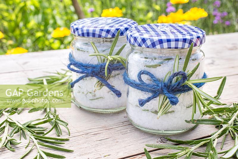 Homemade rosemary salt, made using sea salt and leaves of Rosmarinus officinalis, in glass jars, tied with string
