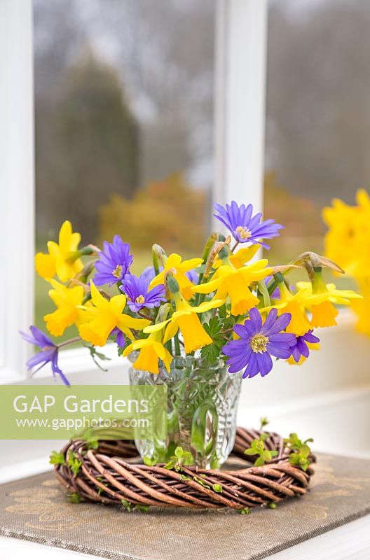 Narcissus and Anemone in a glass jar within woven willow wreath
