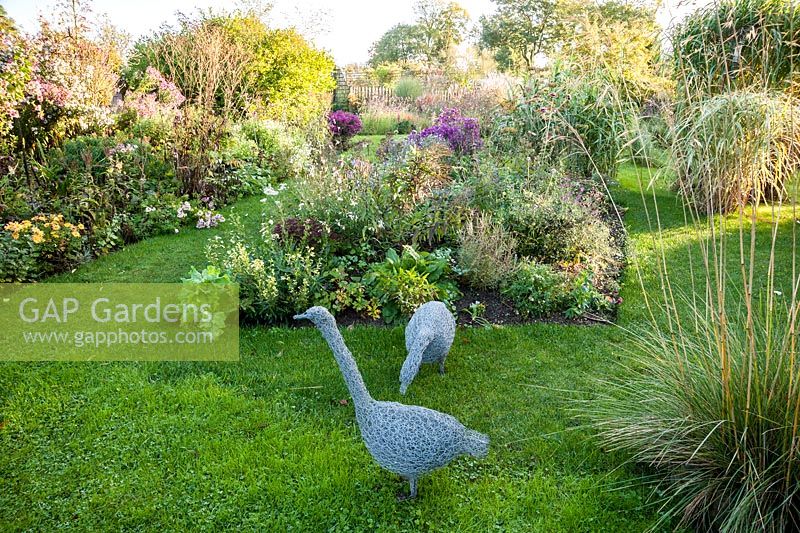 Wirework geese surrounded by grasses and late season flowering perennials including asters and chrysanthemums. Norwell Nurseries, Norwell, Notts, UK