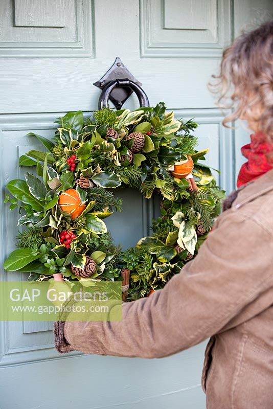 Gabbi Reid hanging completed Christmas wreath on a door. Gabbi's Garden, December.