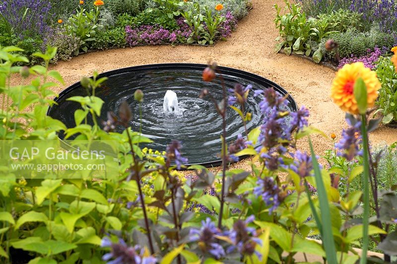Circular water feature surrounded by flower borders