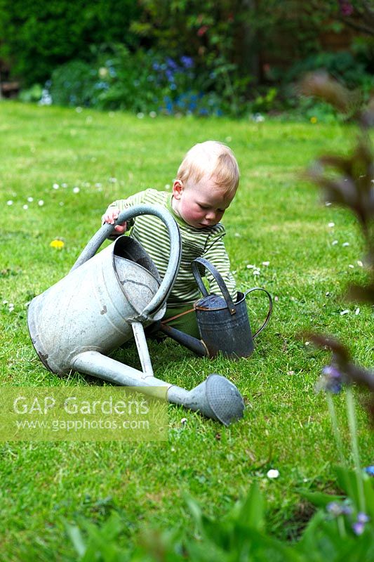 Little boy playing with watering cans