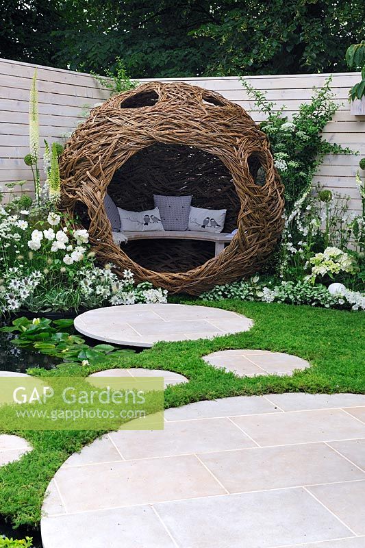 Woven willow bird hide and seating area in bird watcher garden. Chamomile lawn with circular stepping stones - Living Landscapes 'City Twitchers', RHS Hampton Court Flower Show 2015