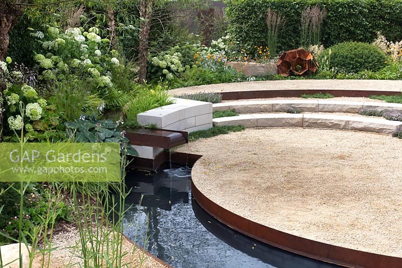 Circular raised steps with metal water channel bordered by lush planting in green and white - Vestra Wealth: Encore - A Music Lover's Garden at RHS Hampton Court Palace Flower Show 2015