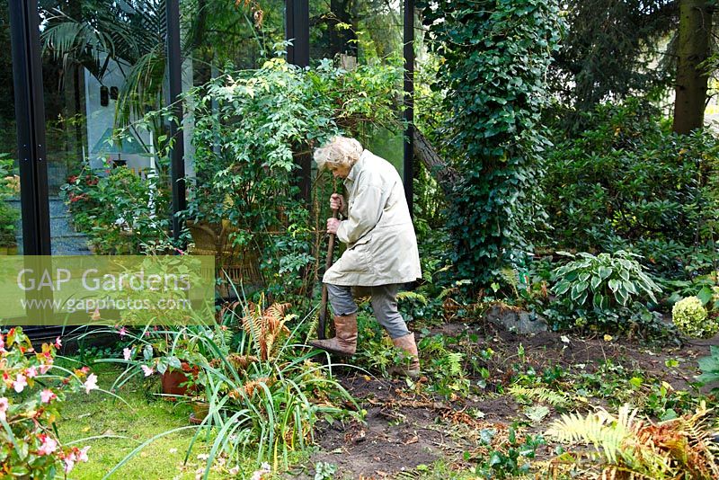 Transform a border: Woman digging out fern - Welsch Garden, Berlin, Germany