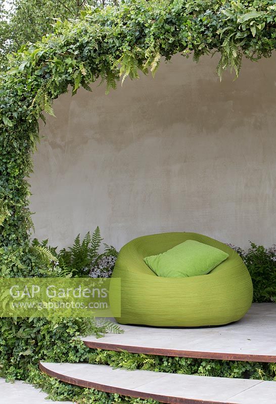 The Macmillan Legacy Garden - contemporary garden shelter with living walls planted with woodland plants, ferns and ivy, raised terrace with green outdoor seat and cushion - Designer Ann Marie Powell - Sponsor Macmillan Cancer Support - RHS Hampton Court Flower Show 2015 - awarded Gold