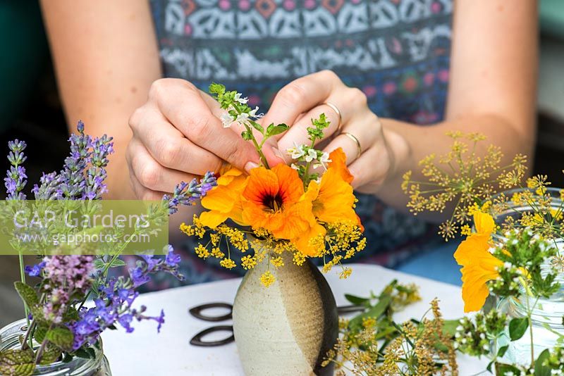 Herbs and edibles posie step by step in August. Stripping stems of basil flowers free of the leaves, before inserting amidst the fennel flowers and nasturtiums.