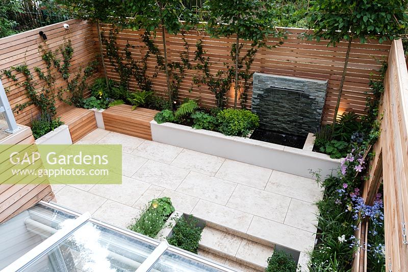 Red cedar wall screen and bench, Sofia limestone paving, slate water feature, Carpinus betulus pleached, Trachelopermum jasminoides, Clematis 'Nelly Moser', Agapanthus africanus, Agapanthus africanus 'Alba'