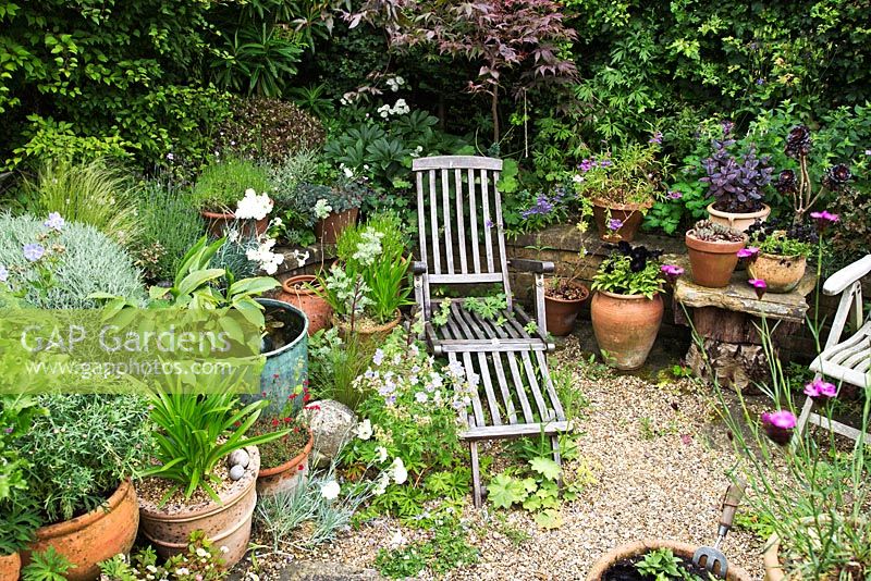 Wooden loungers surrounded by containers. Village of Fordcome, Kent - where a number of cottages opened up their gardens for the day.