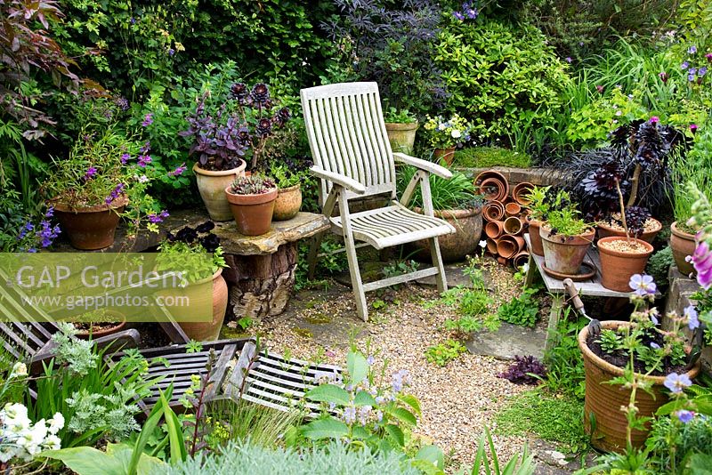 Wooden loungers surrounded by containers. Village of Fordcome, Kent - where a number of cottages opened up their gardens for the day.
