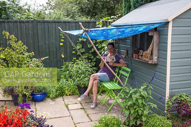 Woman reading a book and drinking tea under a blue awning