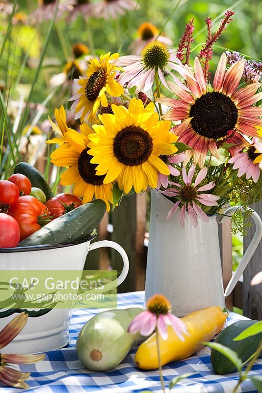 Floral and harvest display - jug of sunflowers, tomatoes, cucumbers, courgettes.