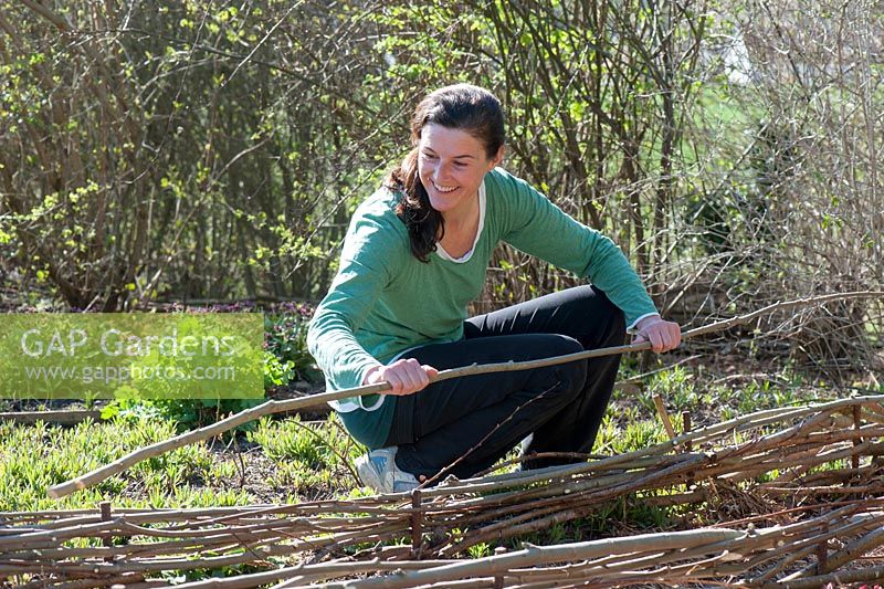 Woman creating a bed enclosure from branches