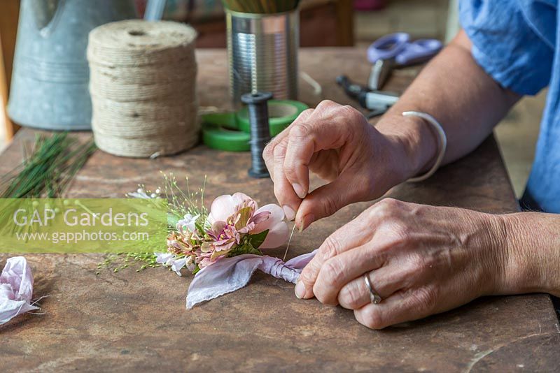 Adding a pin to the buttonhole so it can be worn. Zinnia elegans 'Queen Red Lime', Rosa 'Ambridge Rose', Panicum elegans 'Frosted Explosion' and Abelia x grandiflora