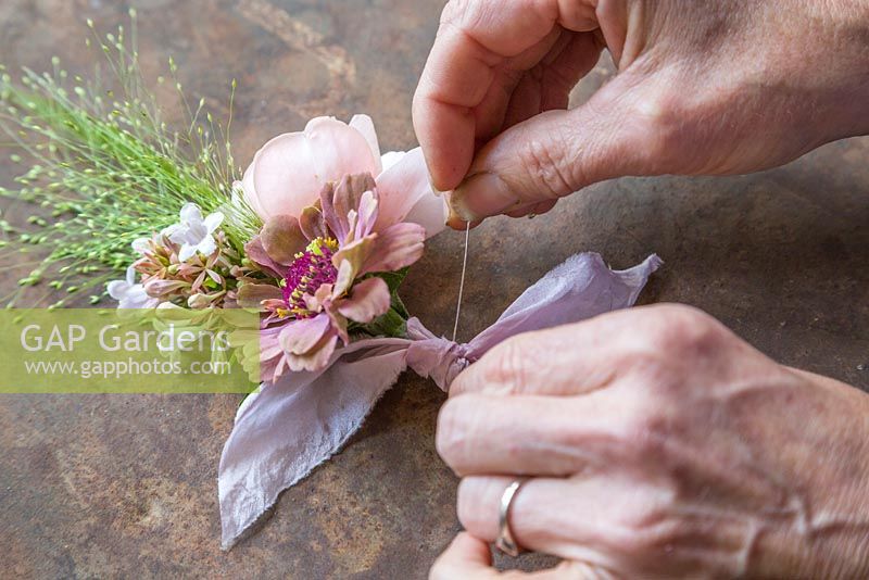 Adding a pin to the buttonhole so it can be worn. Zinnia elegans 'Queen Red Lime', Rosa 'Ambridge Rose', Panicum elegans 'Frosted Explosion' and Abelia x grandiflora