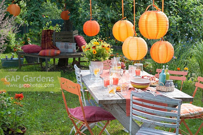 Garden decorated for party with orange lanterns as decoration: Bouquet of calendula, Helenium and Alchemilla 
