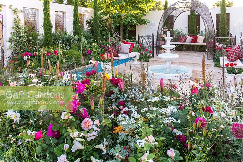 Garden of Paradise. Turkish Tourism Board. RHS Hampton Court Palace Flower Show 2015. A garden featuring traditional Islamic elements. White marble fountain, geometric architecture, moving and still water, Cypress trees, mixed borders with scented roses, lilies and herbs. Rosa 'Darcey Bussell' and Rosa 'The Lady Gardener'.