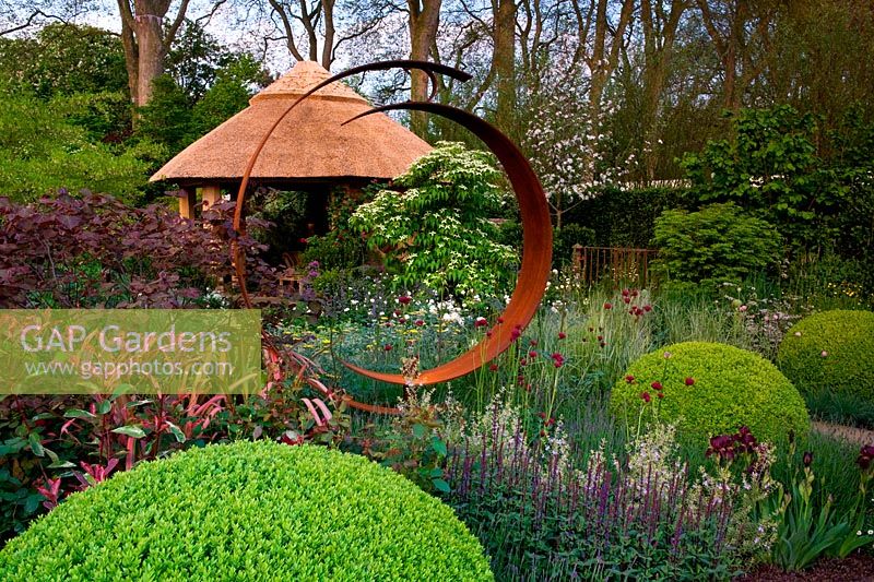 Marcus Harpur Centenary M and G Investments Centenary Windows Through Time. Chelsea Flower Show.  Gold medal winner.  Steel circle sculpture with thatched garden building. Design: Roger Platts Sponsor: M and G 