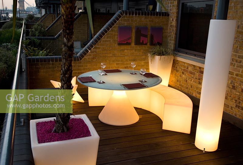 Contemporary balcony overlooking the Thames at Wapping with white plastic illuminated dining furniture