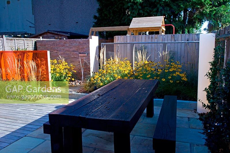 Small urban contemporary town garden bench seat and dining table on decked patio terrace.  Ansari garden, Harrow