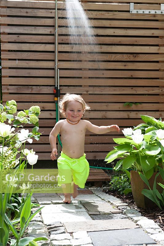 Child running through water jet from outdoor shower