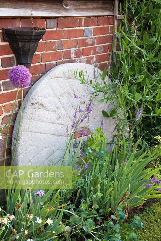Decorative mill stone in country garden. Bradness Gallery, East Sussex. Owners: Artists Michael Cruickshank and Emma Burnett