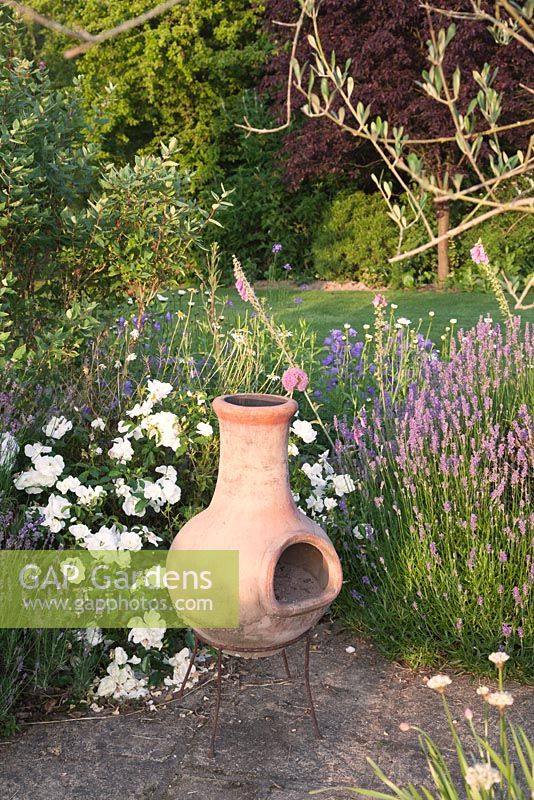Terracotta chiminea on garden patio with Rosa and Lavender. Bradness Gallery, East Sussex. Owners: Artists Michael Cruickshank and Emma Burnett