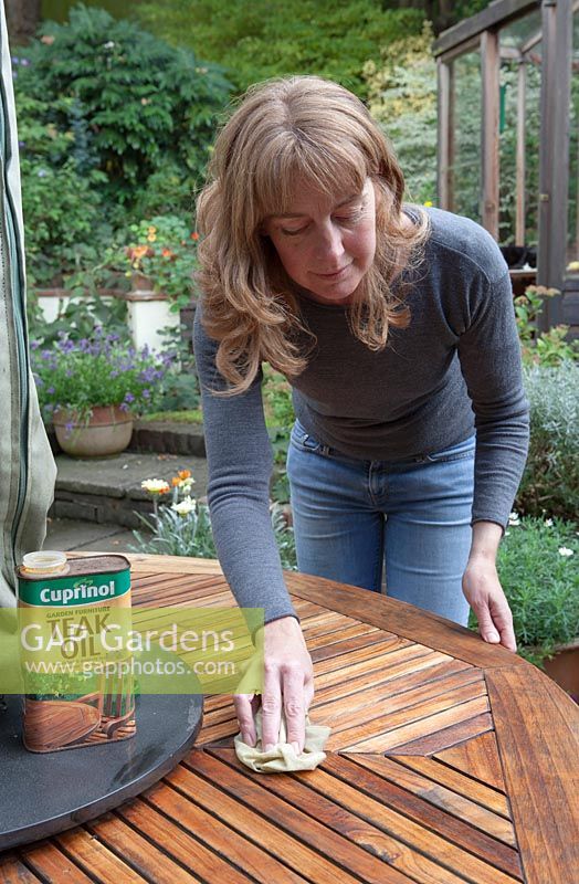 Lady treating a garden patio table with Teak Oil