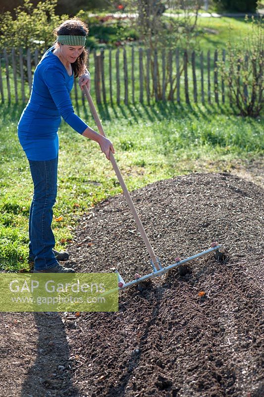 Woman raking compost on newly created bed