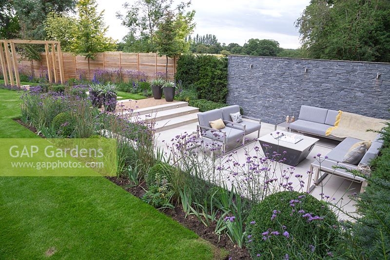 Overview of the sunken seating area surrounded by a border of Verbena bonariensis, Calamagrostis x acutiflora 'Karl Foerster' and Buxus sempervirens balls used to give a sense of privacy