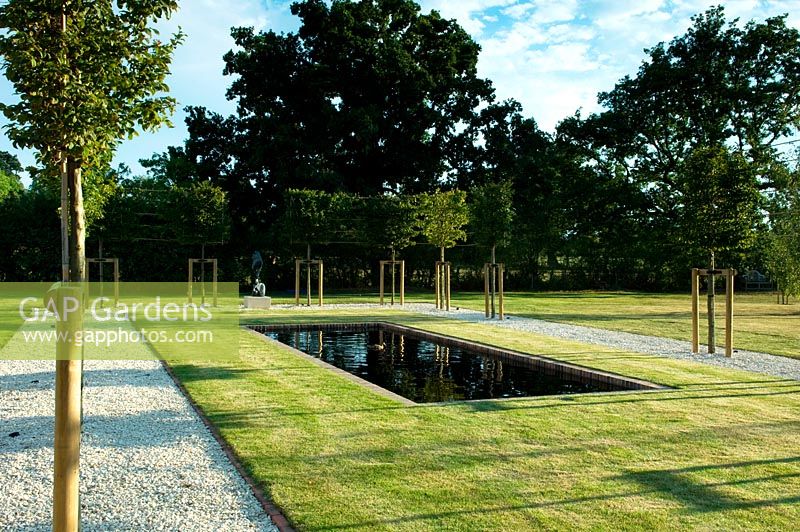 Newly laid out design with courtyard of pleached hornbeams, lawn and a long canal with a focal point sculpture at one end . 