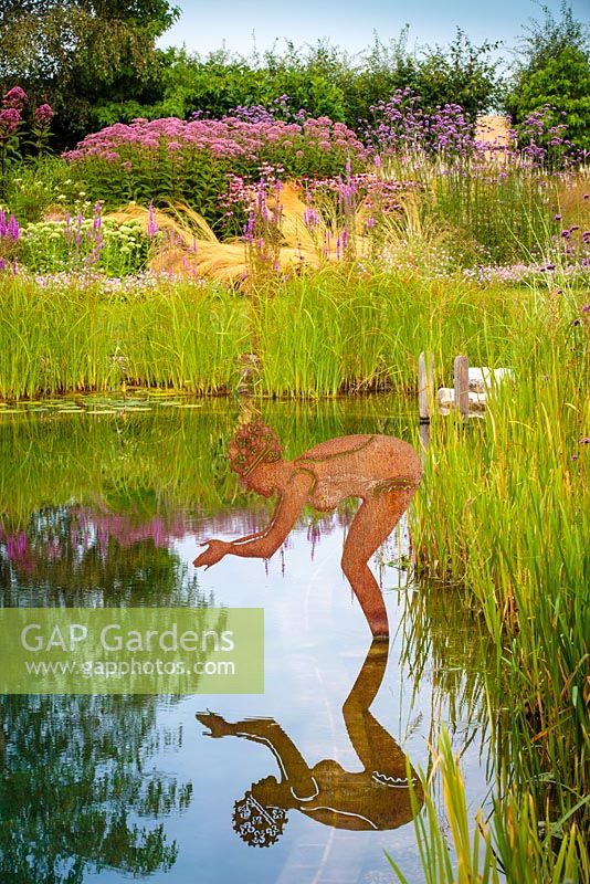 Brushed steel diving lady in a natural swimming pond.