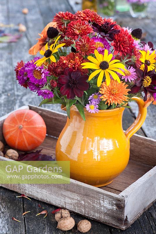 Autumn flowers in pottery vase including cosmos, asters, rudbeckias and chrysanthemums