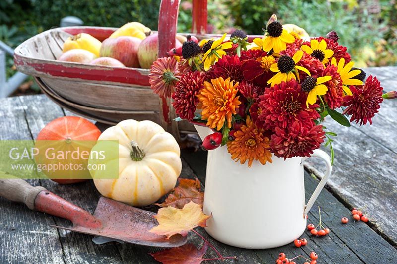 Autumn flowers in jug with trug of fruit and squashes
