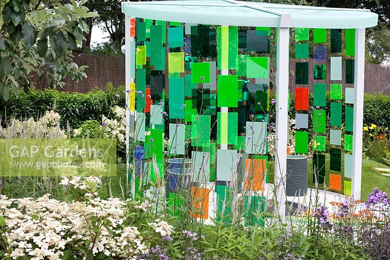 Pavillion made of light reflecting fibre optic panels framed with dense planting in 'Reflecting Photonics' Garden at RHS Tatton Flower Show