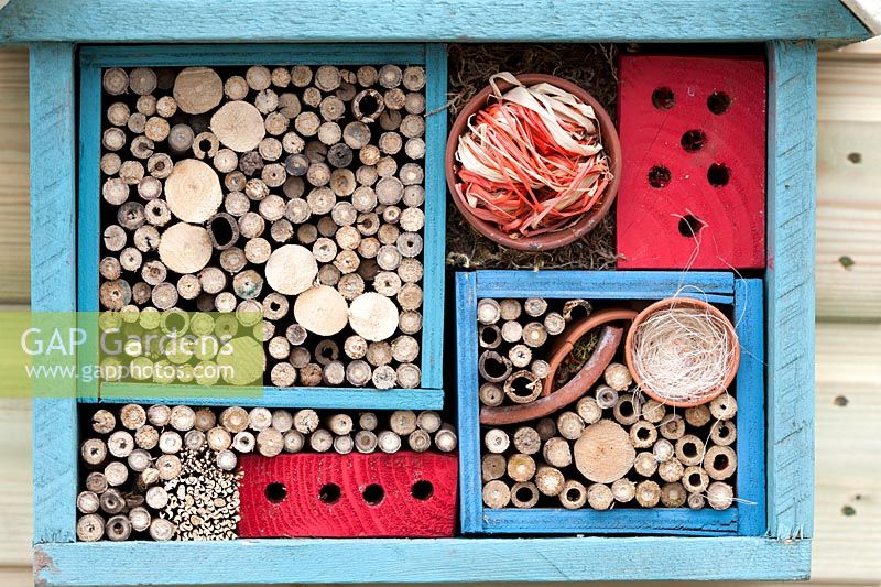 Bug hotel made from wooden boxes filled with sticks and broken teracotta plant pots