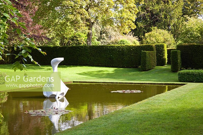 A contemporary Japanese pond garden. White marble sculpture 'Hokusai's boat' by Jessica Walters. Designer Georgia Langton. Farleigh House, Hampshire.