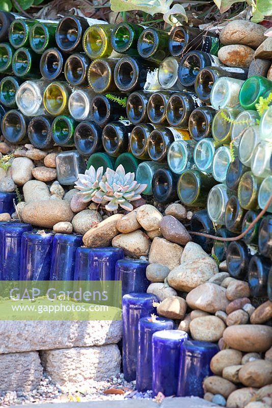 Succulents planted against wall made of glass bottles in Jim Bishop's Garden. San Diego, California, USA. August.