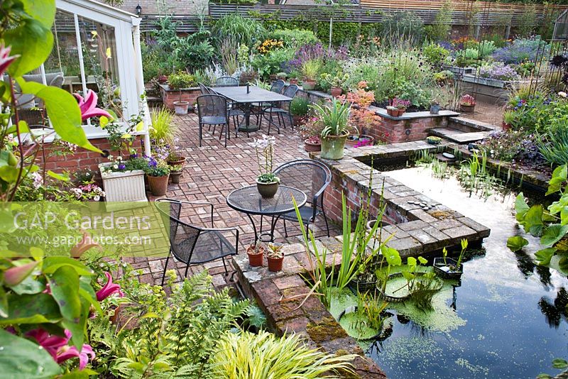 Sunken patio with raised pond and beds of perennials and herbs. The Coach House