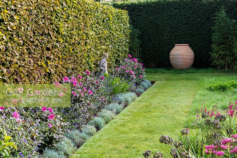 A grass path leading to a terracotta urn focal point with Dahlia 'Roxy', Dianthus and Caryopteris x clandonensis 'Kew Blue'.