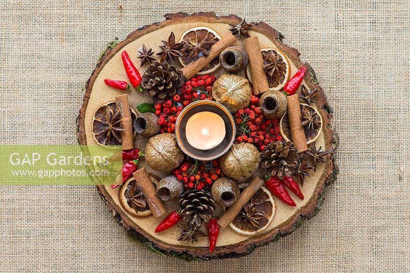 A festive table decoration with dried fruit, nuts, seeds, with freshly picked berries and chilli peppers.