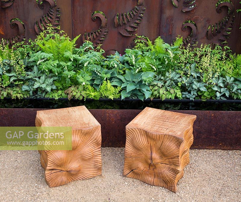 Two carved oak cube seats on gravel path, rusted steel fern wall panel, planting of ferns, hosta, Constraining Nature garden - designed by Kate Durr Garden Design - Best Festival Garden award and a gold medal - RHS Malvern spring festival 2015