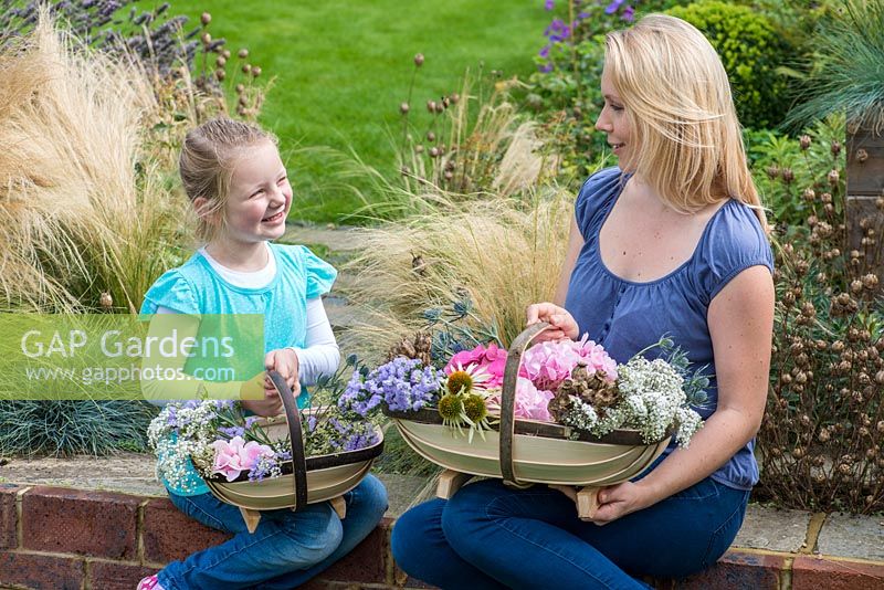 Mother and daughter with their Sussex trugs, handcrafted by Charlie Groves, filled with cut flowers.