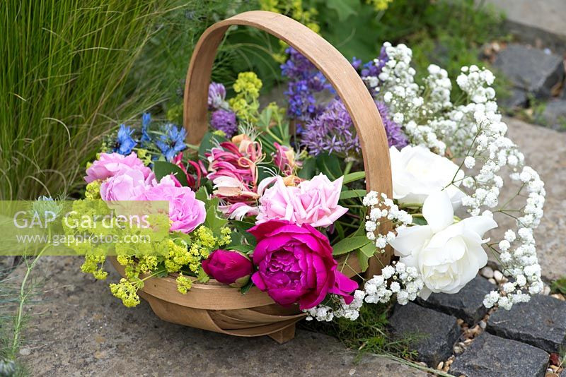 A trug of fresh flowers including roses, peonies, lady's mantle, love in the mist, honeysuckle catmint 