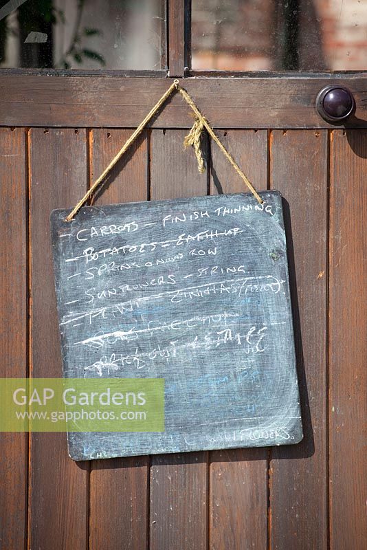 Blackboard with list of jobs to do hung up on greenhouse door