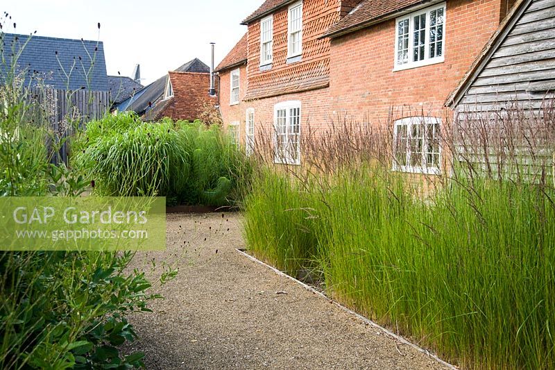The front garden was designed by Christopher Bradley-Hole on a grid pattern, with tall grasses and subtle flowering perennials to give a contemporary meadow feel. Bury Court Barn, Bentley, Hants, UK