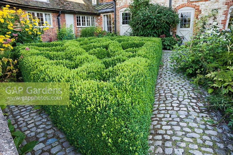 The Courtyard Garden designed by Piet Oudolf and John Coke features a trellis pattern of clipped box in one corner. Bury Court Barn, Bentley, Hants, UK