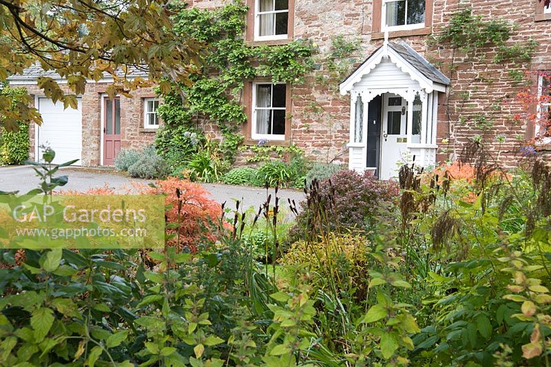 Orange autumn foliage in the front garden reflects the colour of the sandstone house.