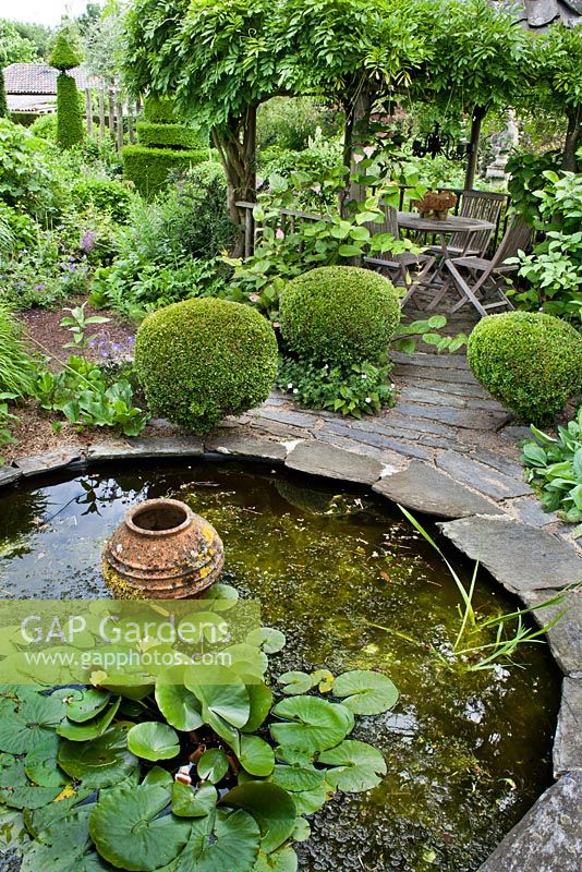 Circular pond with water plants and ornamental urn.